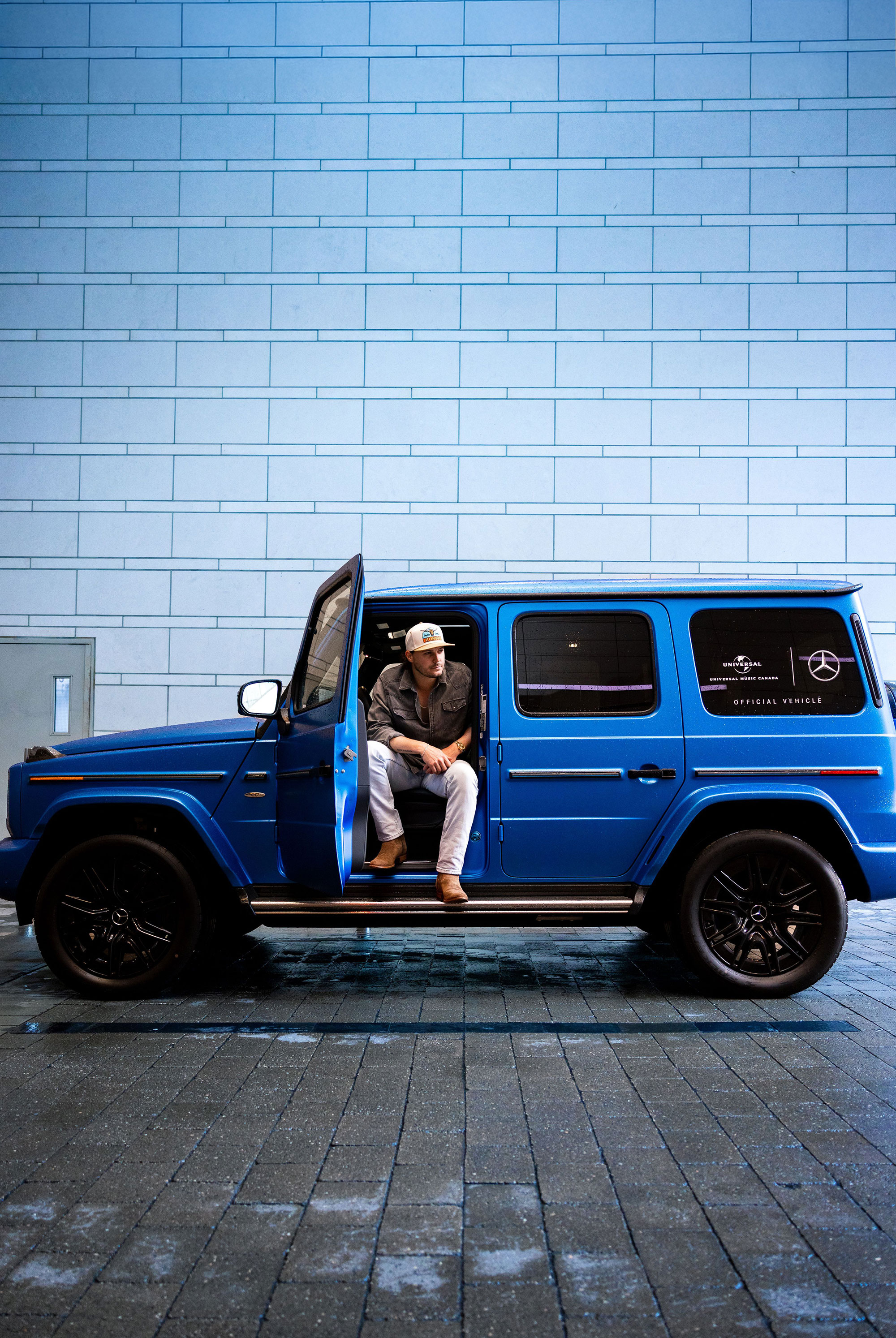 Artist seated in a blue Mercedes-Benz G-Class